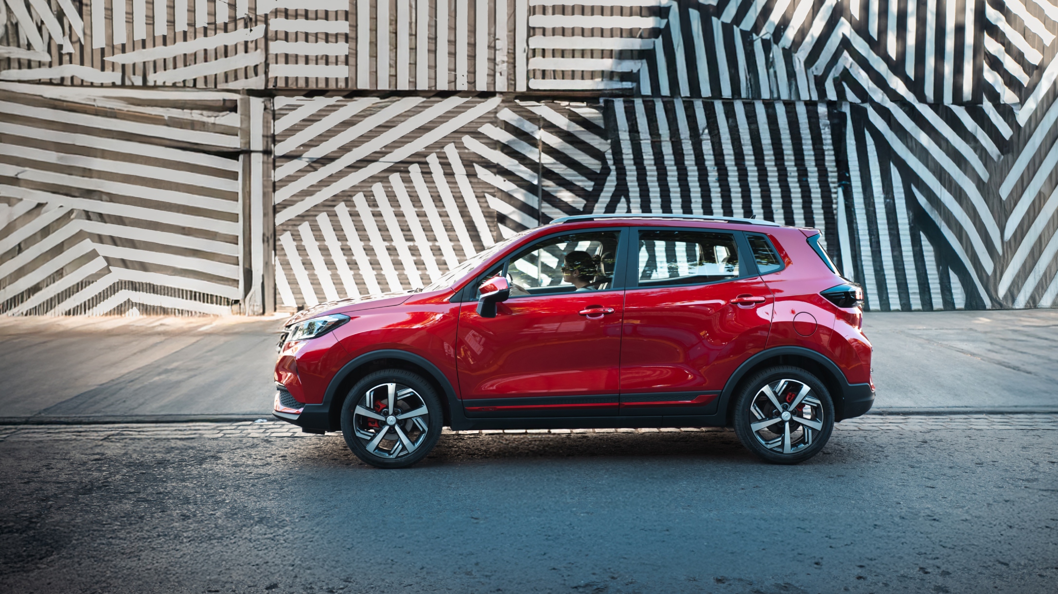 Vista lateral de SUV compacto New Changan CS15 color roja con rines de lujo.