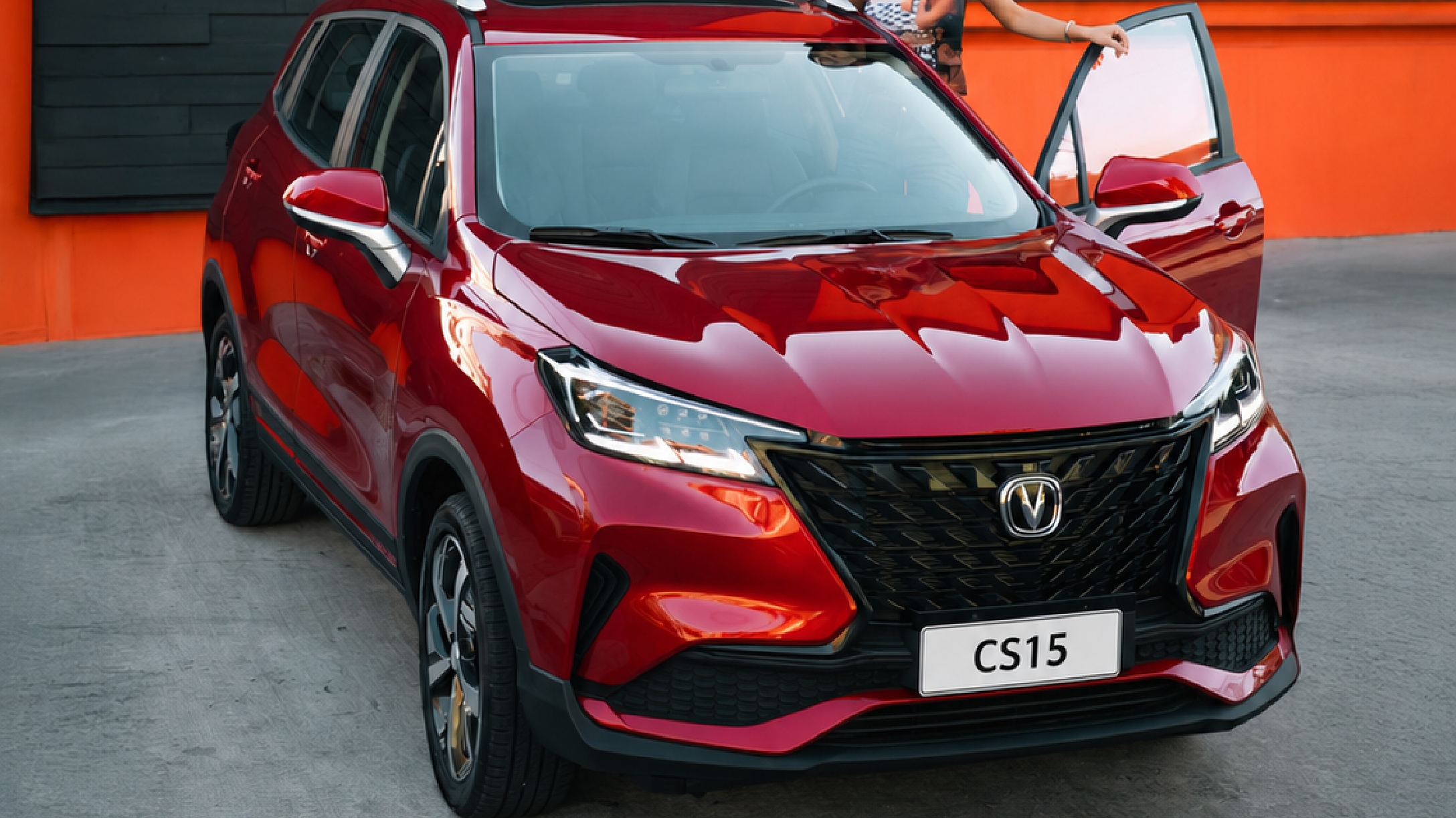 Mujer de pie junto al asiento de conducción del New SUV de Changan CS15 color rojo.